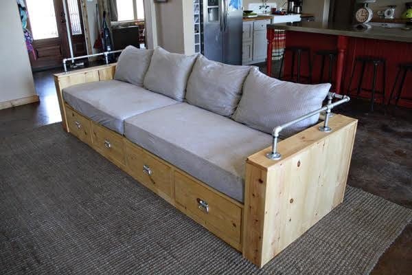Modern wood sofa with hidden storage drawers and a black pipe back rail